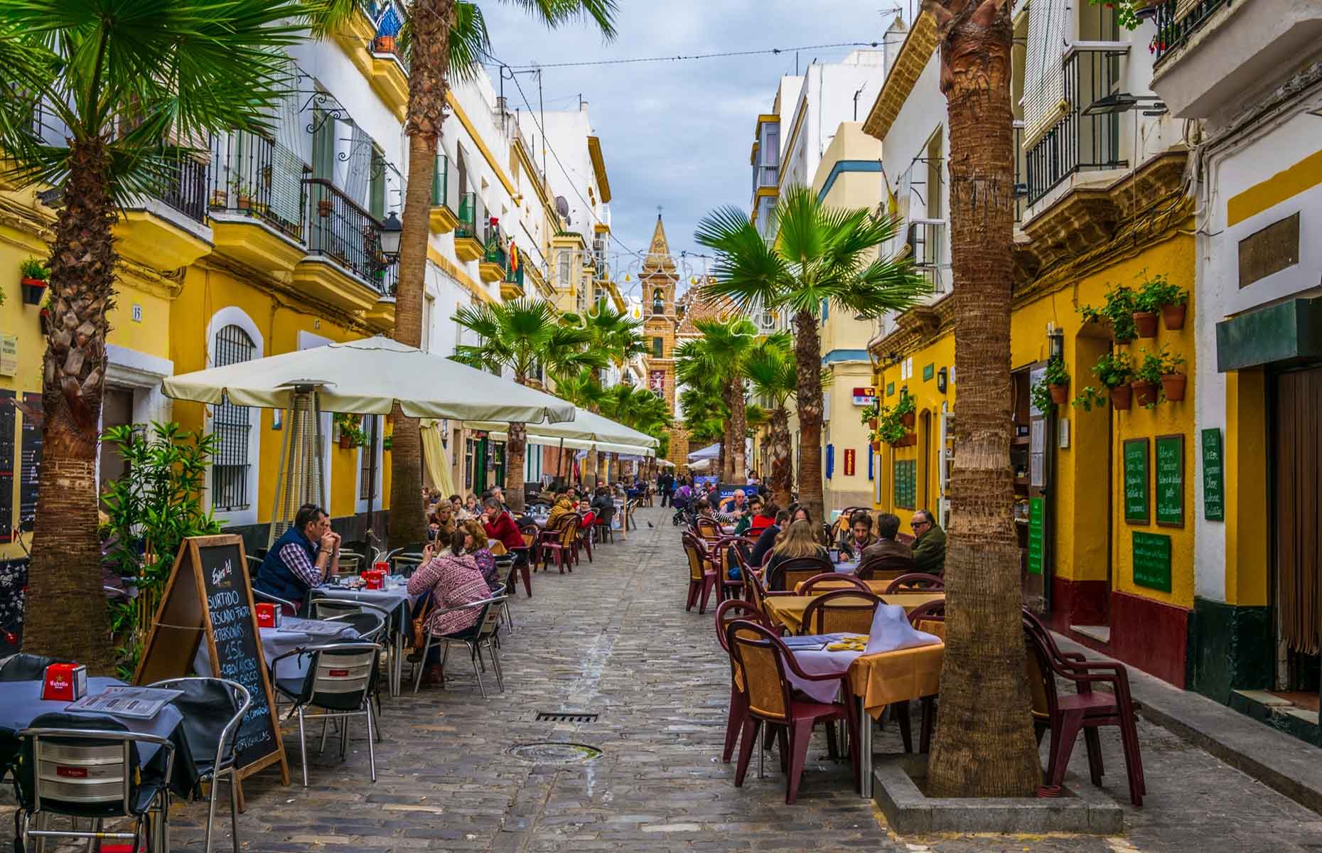 Yellow buildings and palm trees of Cadiz cafe and restaurant street