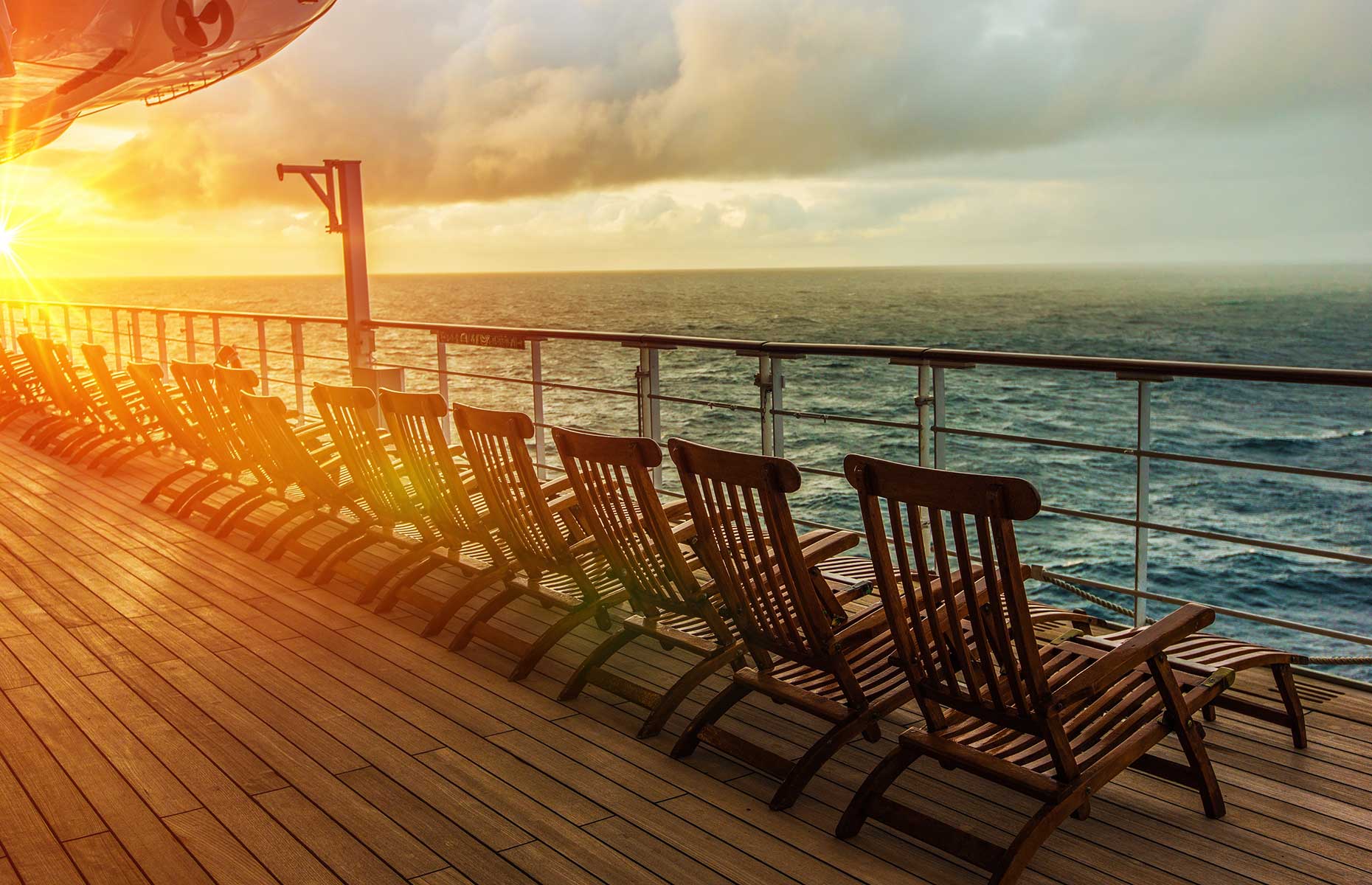 Generic shot of a cruise ship deck with wooden deck chairs facing the sea and the setting sun (Image:  By Virrage Images/Shutterstock))