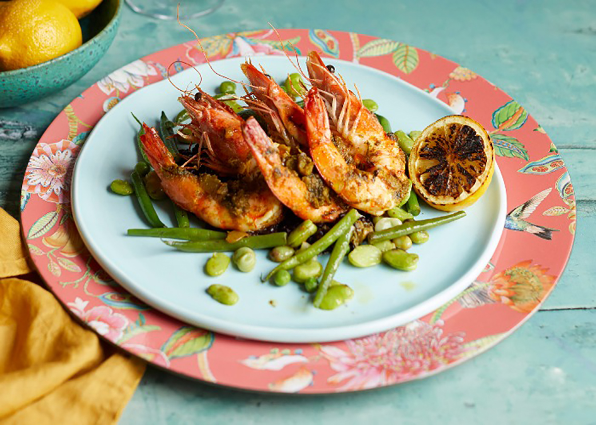 grilled whole prawns atop broad beans on samon-coloured plate