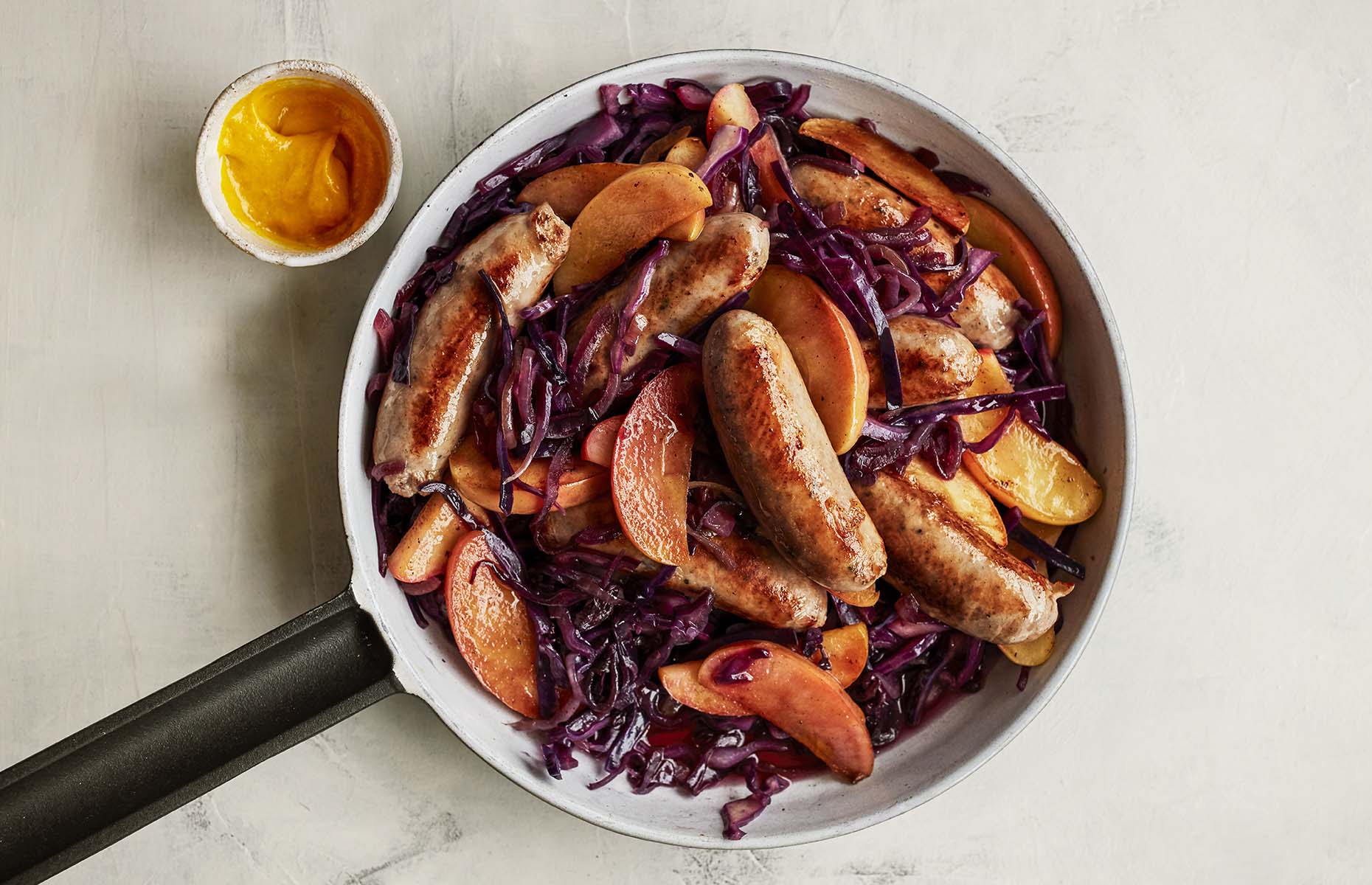 Braised red cabbage, apples and sausages (Image: Waitrose & Partners/loveFOOD)