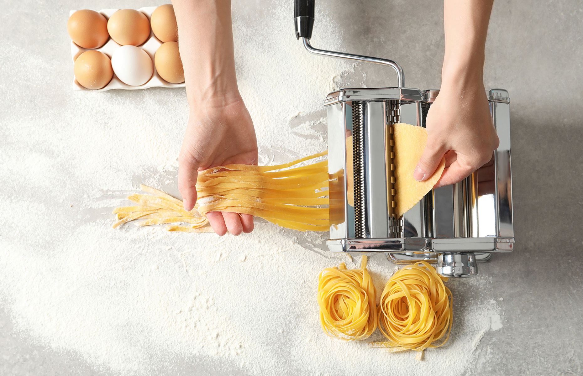 Homemade pasta noodles taking shape in a machine