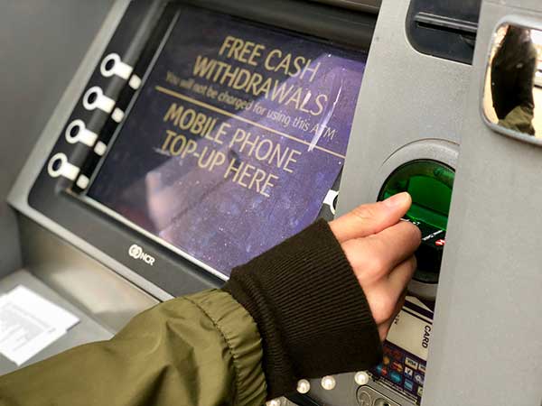 Person using ATM. (Image: photocritical/Shutterstock)