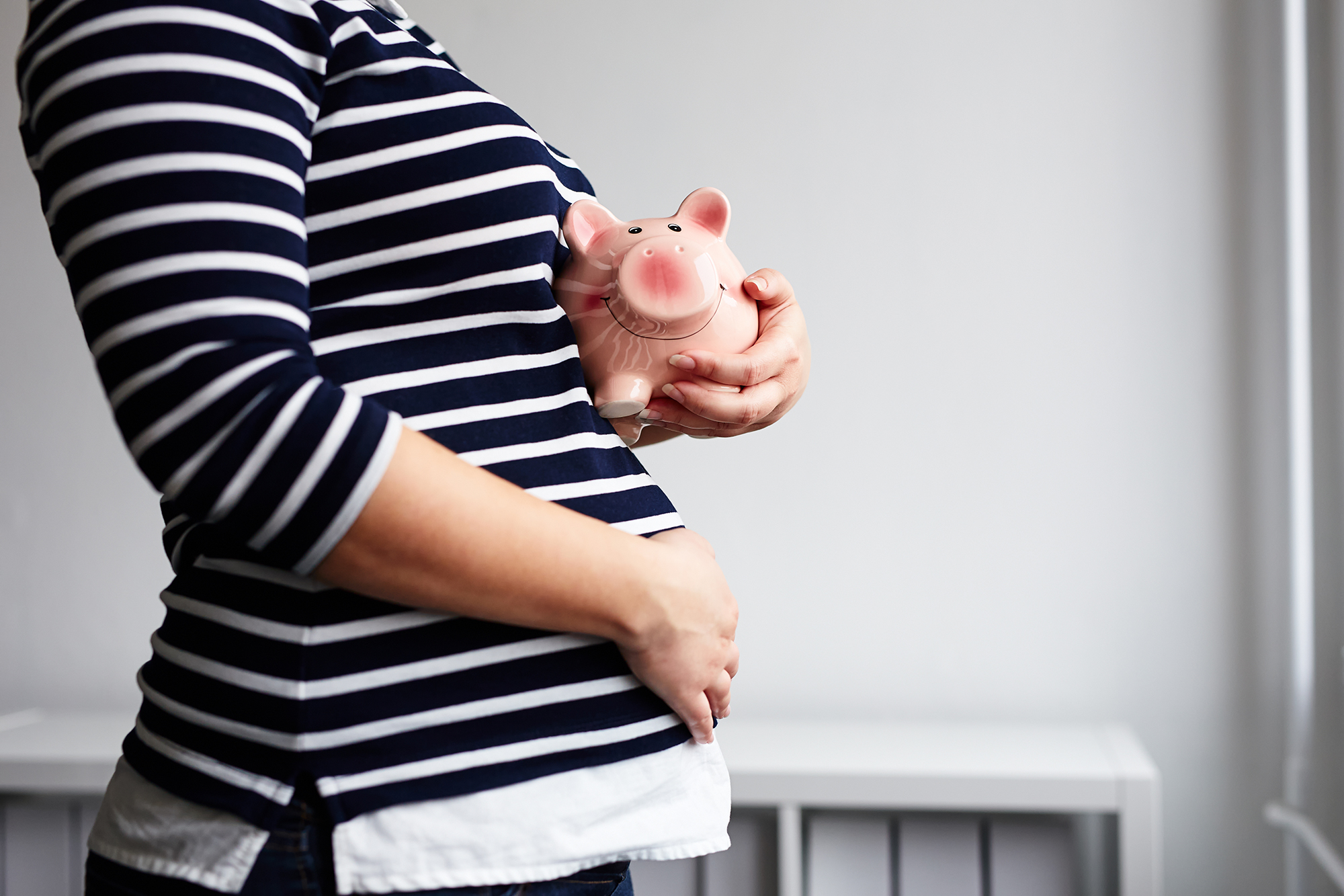 Pregnant woman with piggy bank. (Image: Shutterstock)