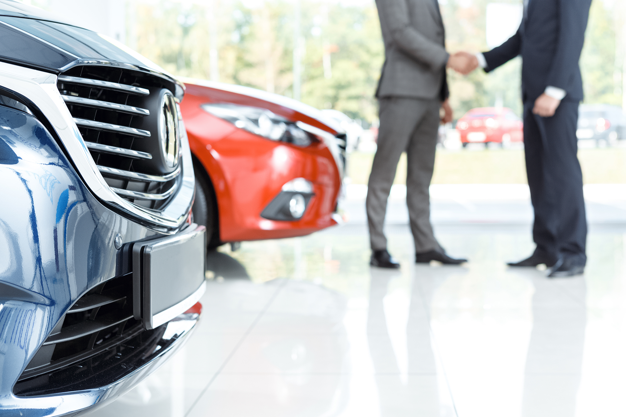 Two men shaking hands at car dealership. (Image: Shutterstock)