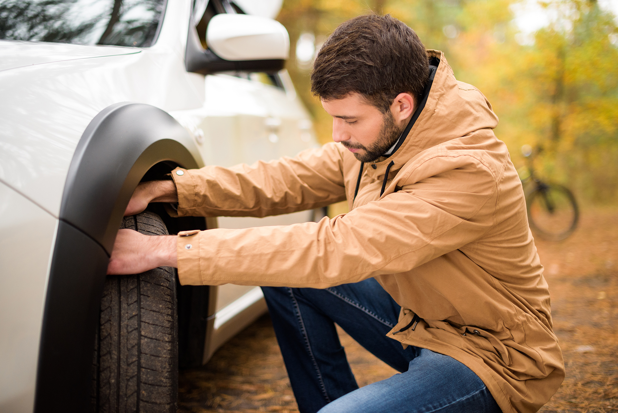 Man checking a car tyre. (Image: Shutterstock)