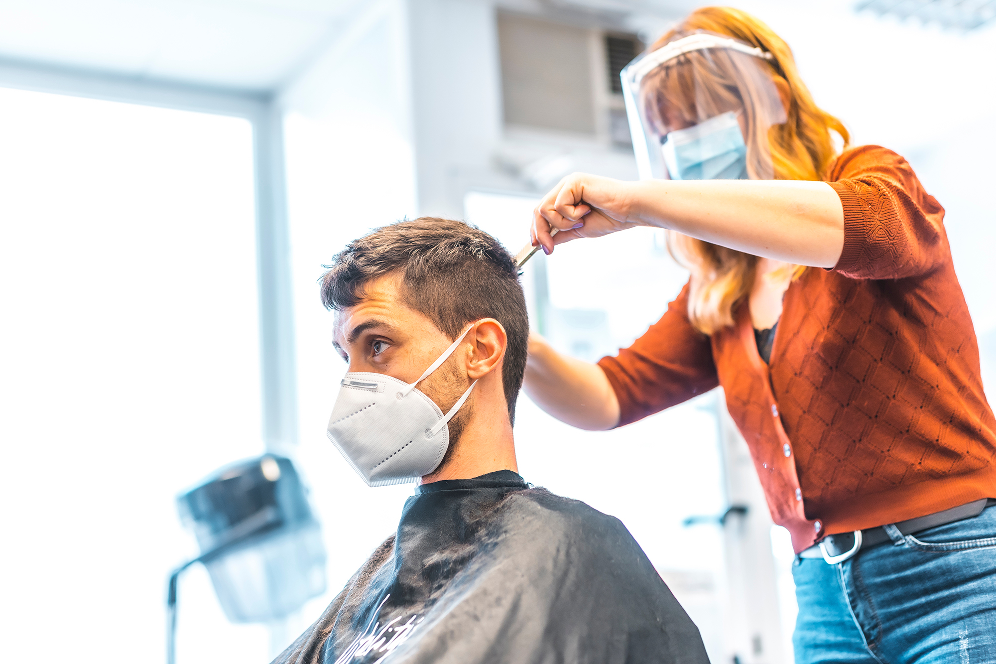 Woman cutting a man's hair. (Image: Shutterstock)