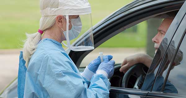 Woman testing a man at a drive-through testing area. (Image: Shutterstock)