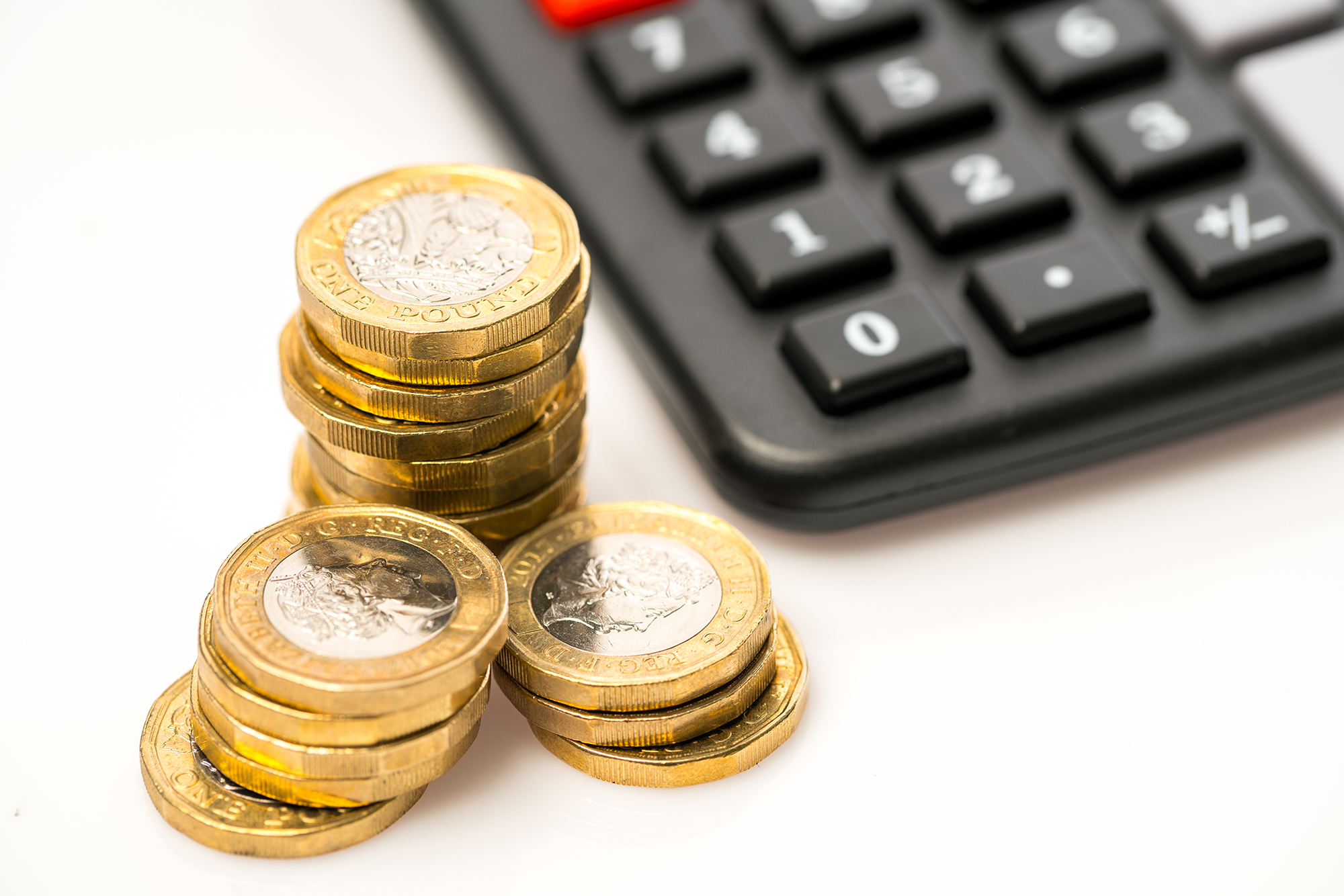 Pound coins next to calculator. (Image: Shutterstock)