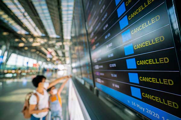 Woman looking at board announcing cancelled flights. (Image: Shutterstock)