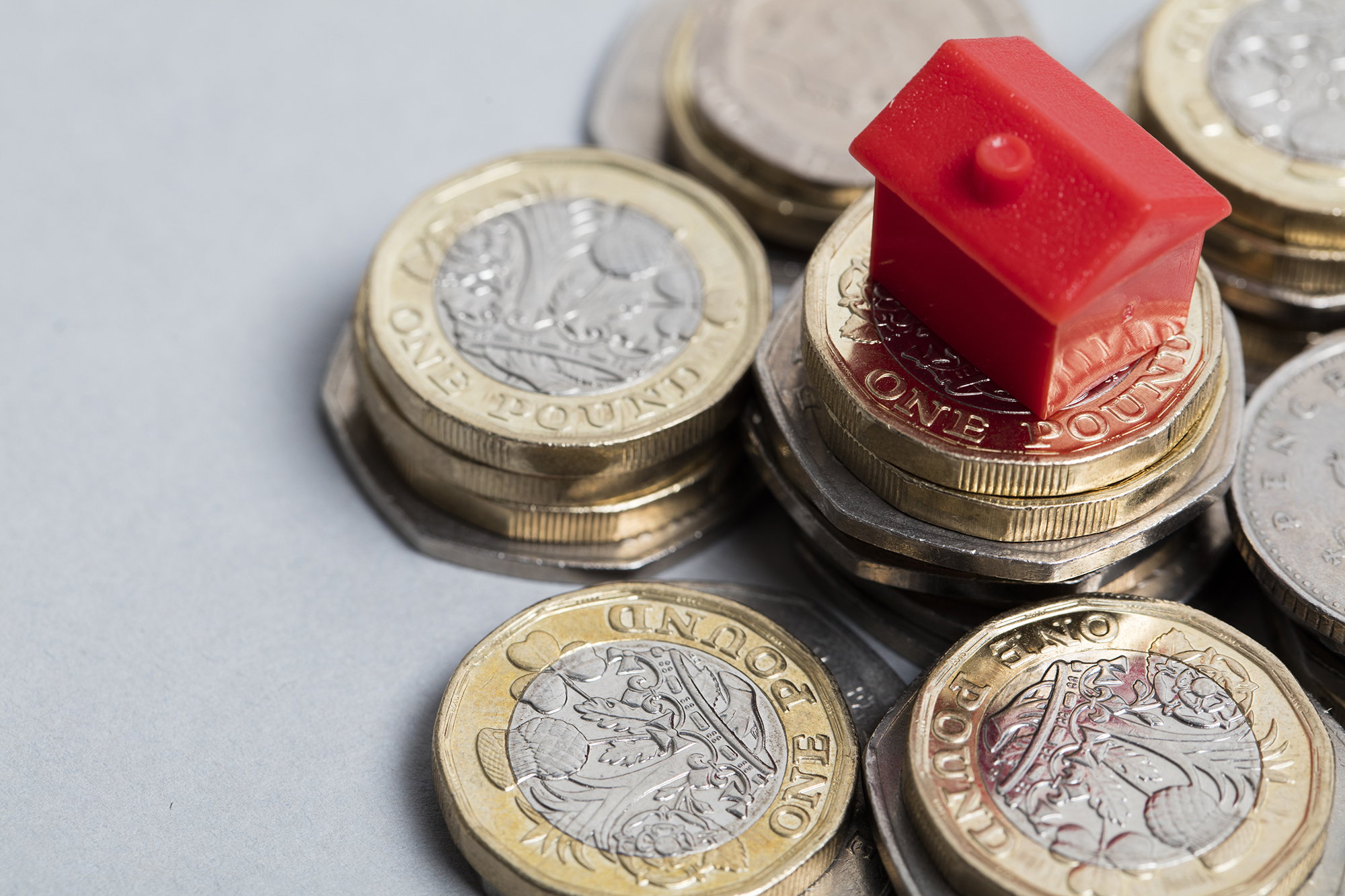 Miniature house on top of coins. (Image: Shutterstock)