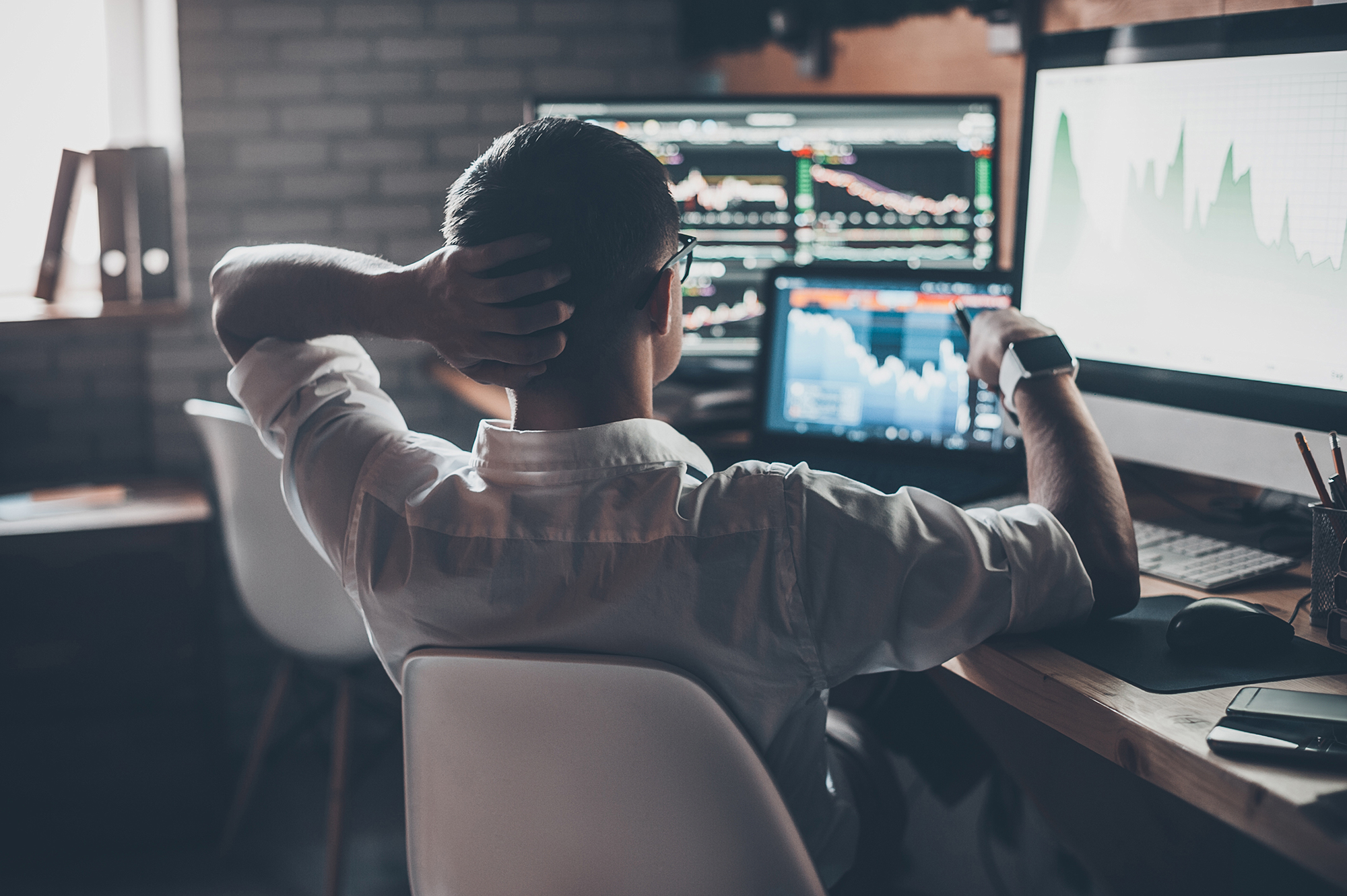 Man at desk looking at investments. (Image: Shutterstock)