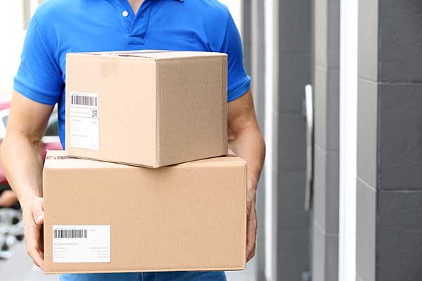 Courier holding parcels. (Image: Shutterstock)