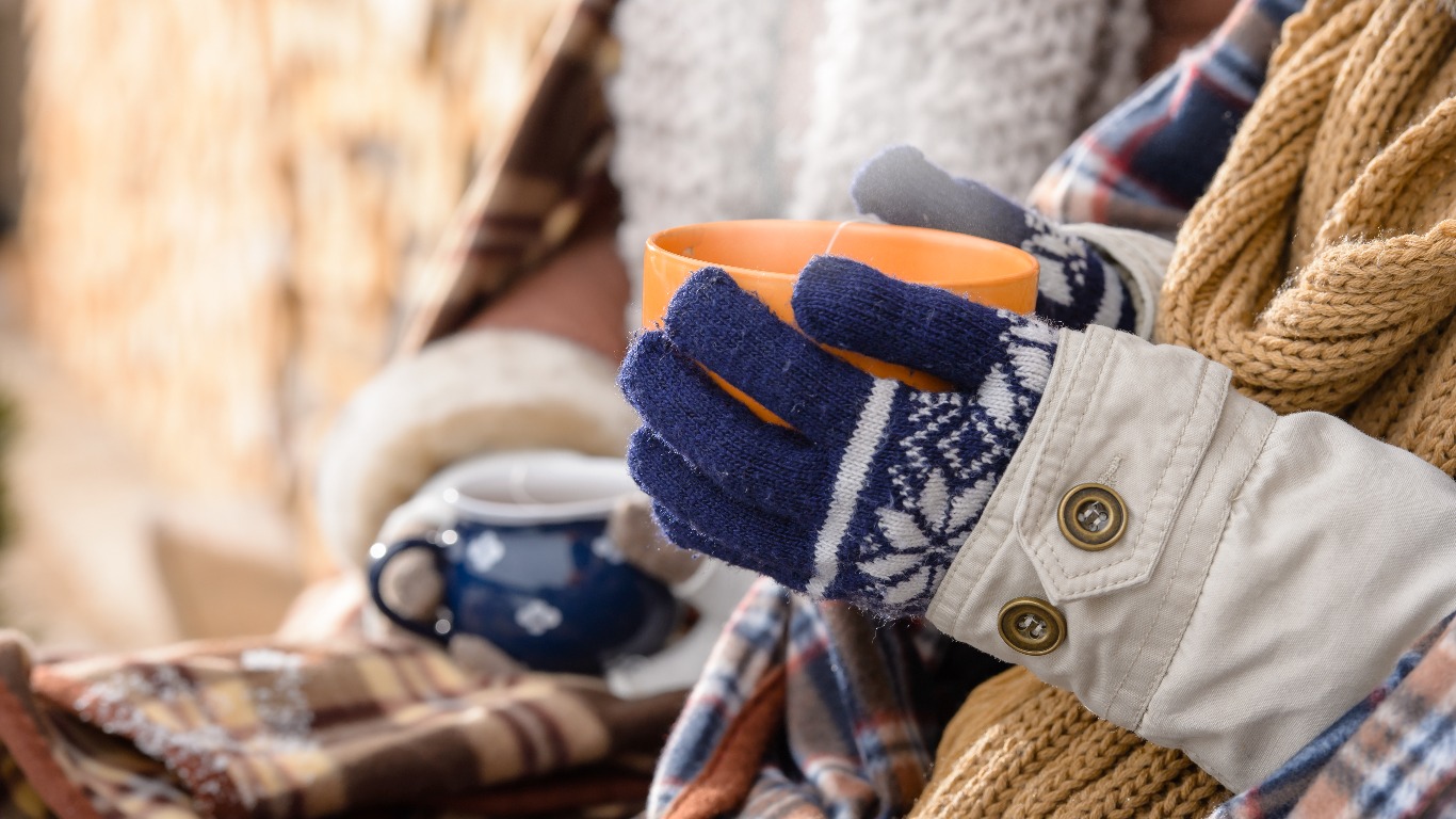 Woman wearing scarf and holding a hot drink. (Image: Shutterstock)