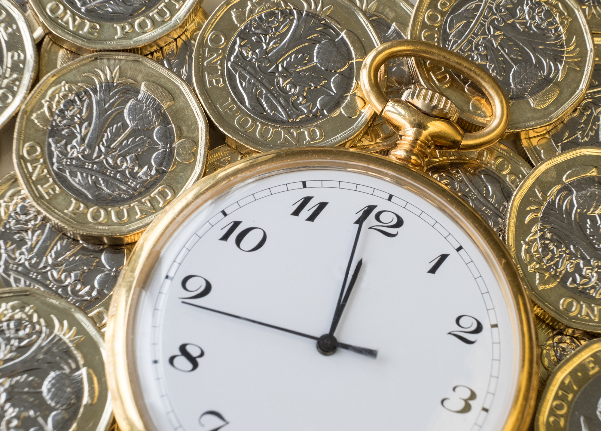 Gold watch surrounded by pound coins. (Image: Shutterstock)