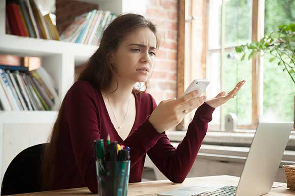 Frustrated young woman using phone. (Image: Shutterstock)