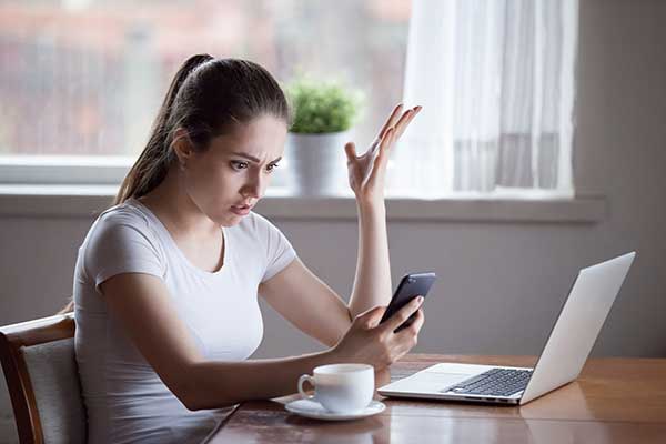 Shocked woman looking at phone. (Image: Shutterstock)