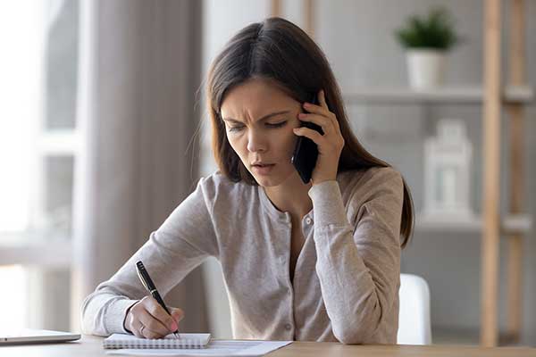 Worried woman writing on a notepad. (Image: Shutterstock)