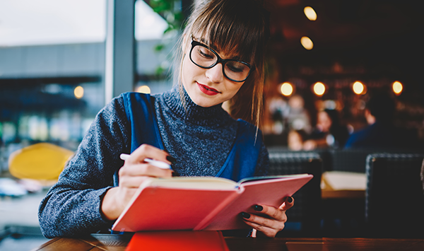 A woman writing down expenditure in a diary. 