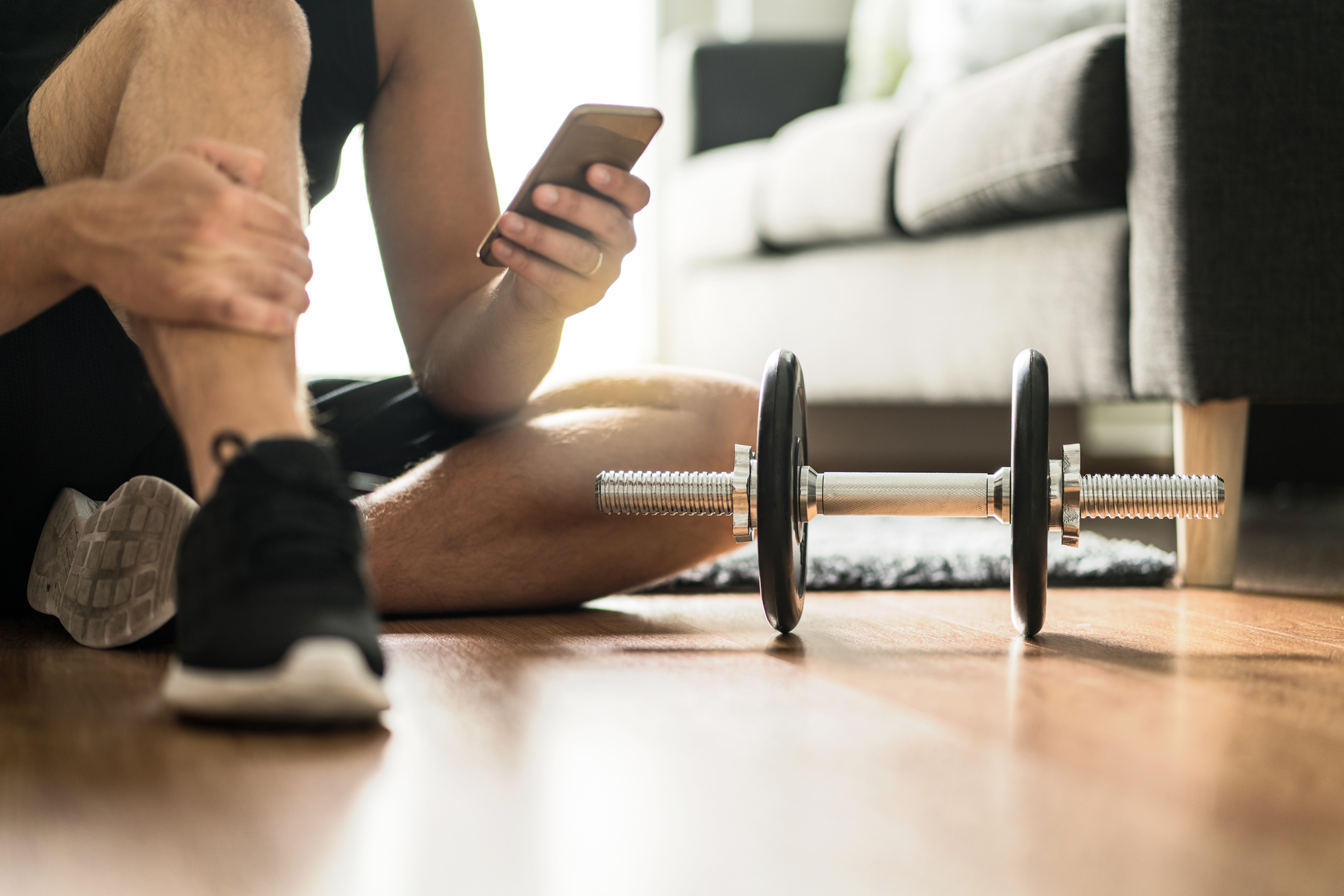 Man on smartphone next to a weight. (Image: Shutterstock)