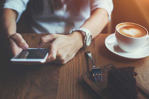 Woman using phone in a cafe. (Image: Shutterstock)