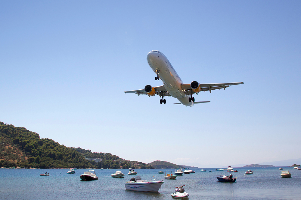 Image by Neil Lang / Shutterstock. A plane lands over the seain Greece