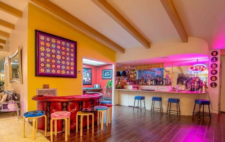 This colourful party room features a poker table, pink backlighting and a mirrored wall. Image: Berkshire Hathaway