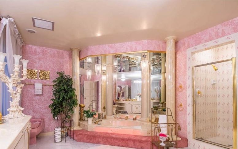 Marble pillars frame an opulent corner bath, complete with a pink carpeted step. Image: Berkshire Hathaway